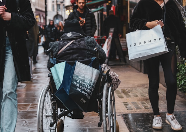 A wheelchair user navigating a busy shopping street in London.
