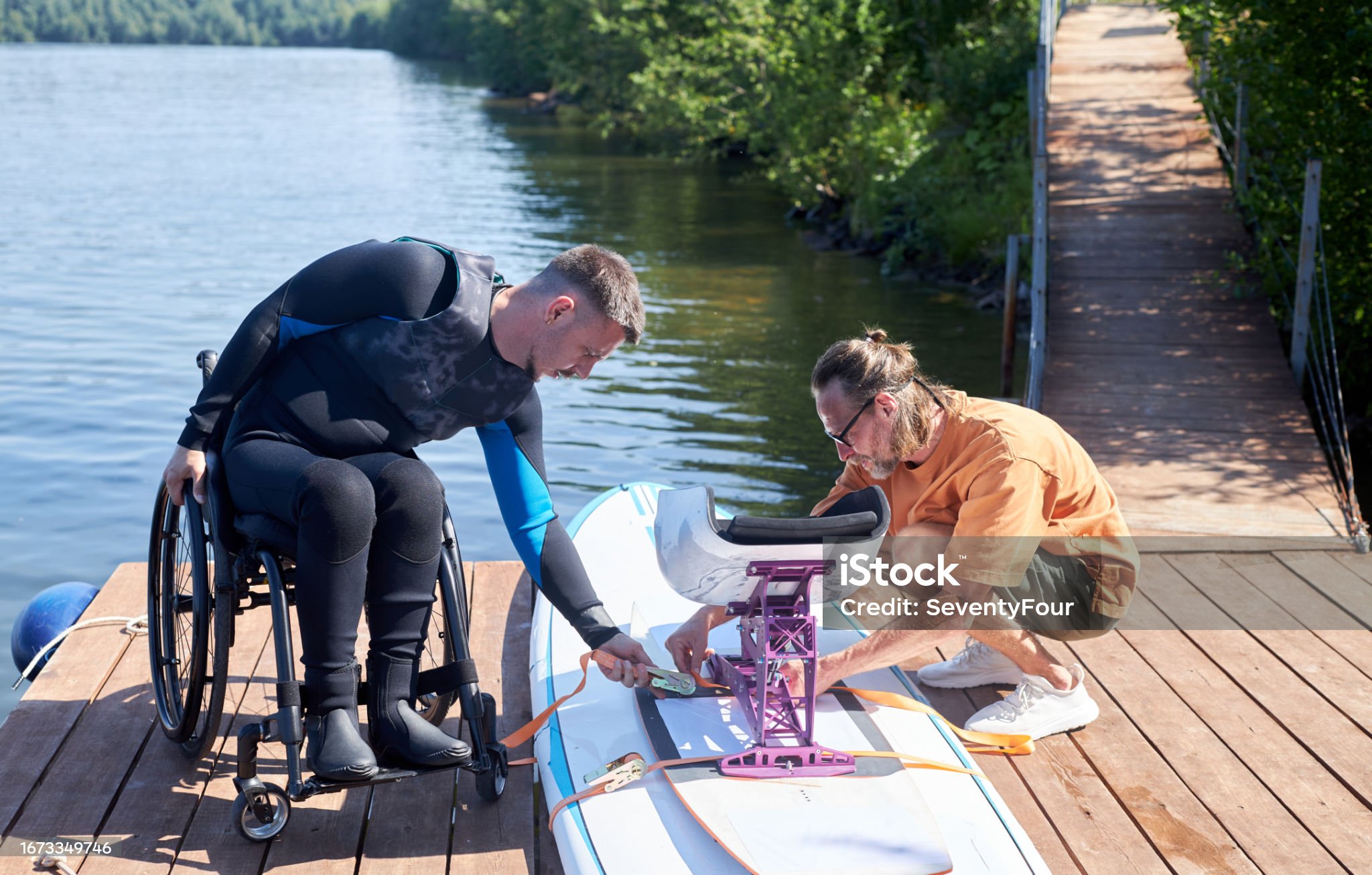 A man in a wheelchair preparing adaptive water equipment on a dock.