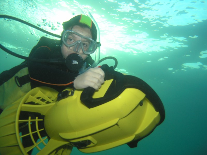A diver underwater using a yellow diver propulsion vehicle.